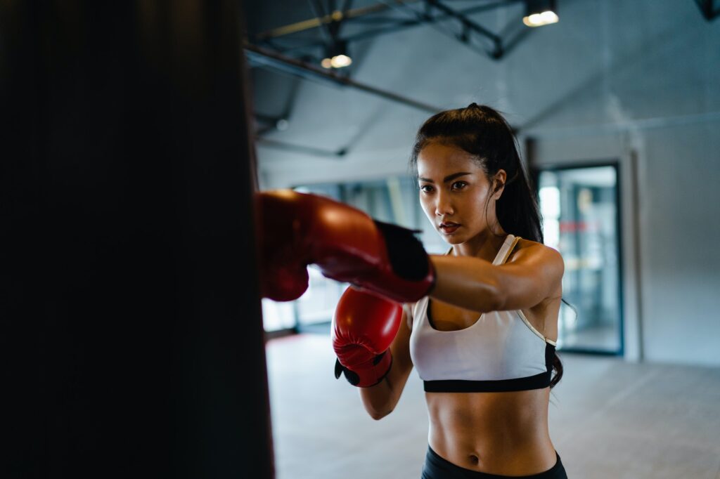 Asia lady kickboxing exercise workout punching bag tough female fighter practice boxing.