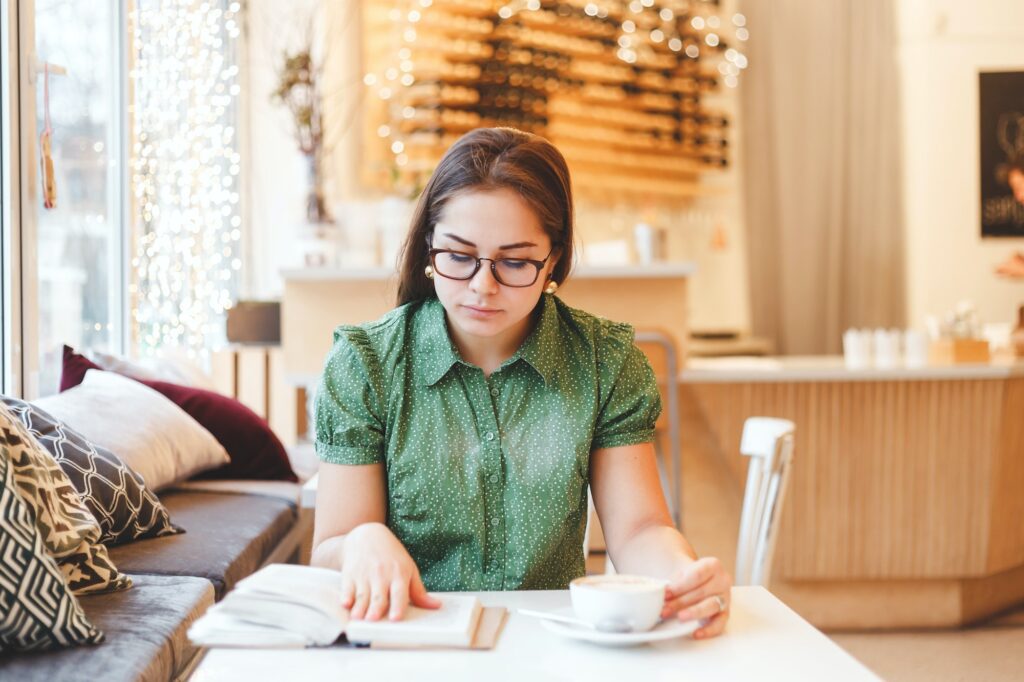 Beautiful young woman relaxing and reading a book in coffee shop