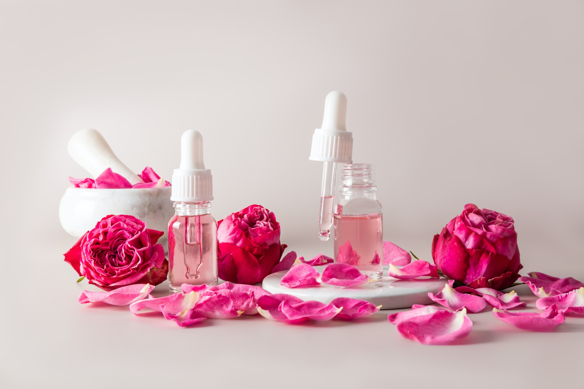 Natural essential oil for home skin care. pink flowers. cosmetic glass bottles with the product