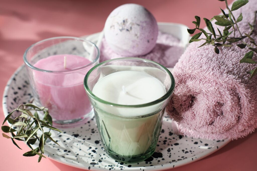 scented soy wax candles and bath bomb and pink towel on pink background. wellness set creating a self-care routine, self-care, relaxing self-care