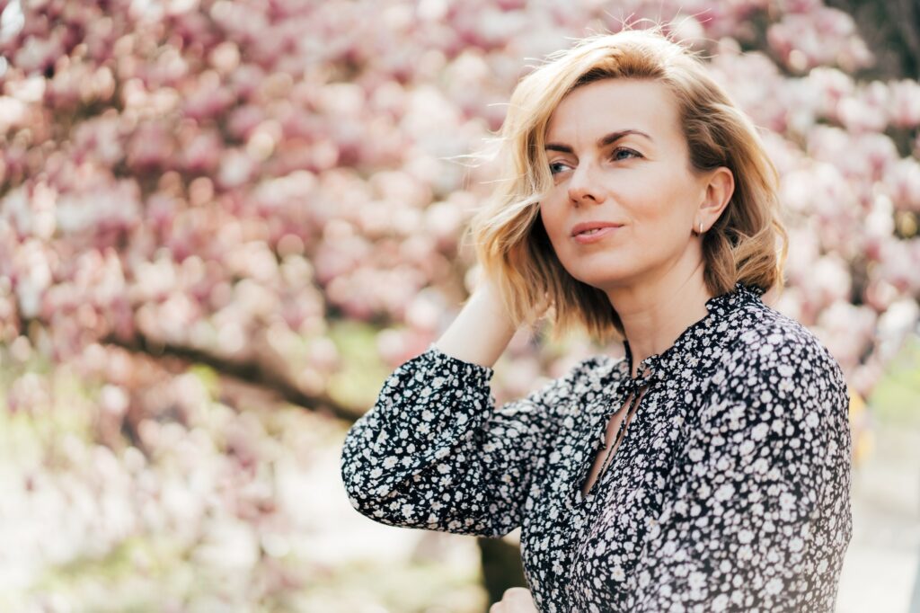 Beautiful woman in her forties. Profile portrait with a pink flowering magnolia tree as background. How Fitness Enhances Natural Beauty