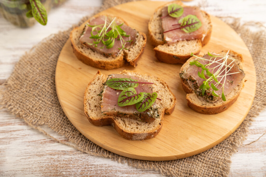 Bread sandwiches with jerky salted meat, sorrel and cilantro microgreen on white