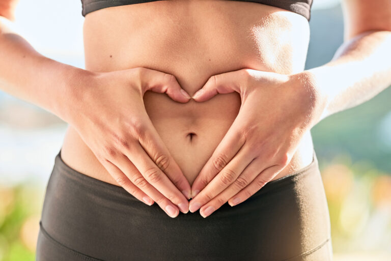 Shot of an unrecognizable young woman making a heart shape with her hands around her belly button