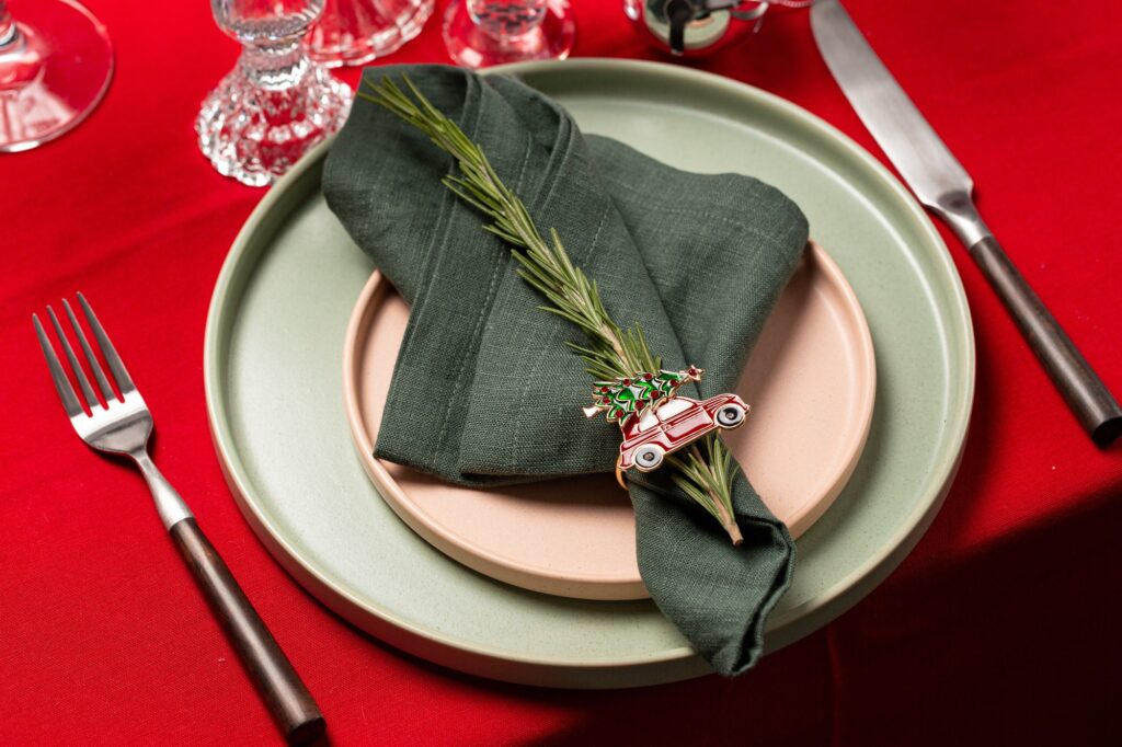 Christmas dinner service, red linen tablecloth, green napkin with a sprig of rosemary, candlesticks