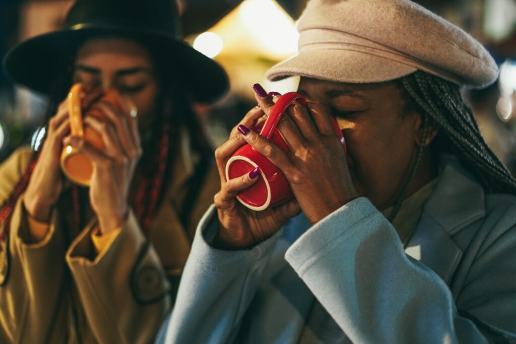 African mother and daughter having fun drinking hot chocolate outdoor in winter time