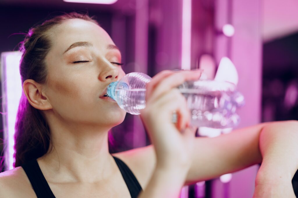 Young sporty woman drinking water in a gym Essential Skincare Tips for Winter