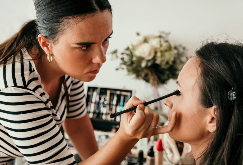 Beautician doing make-up for bride on wedding day.