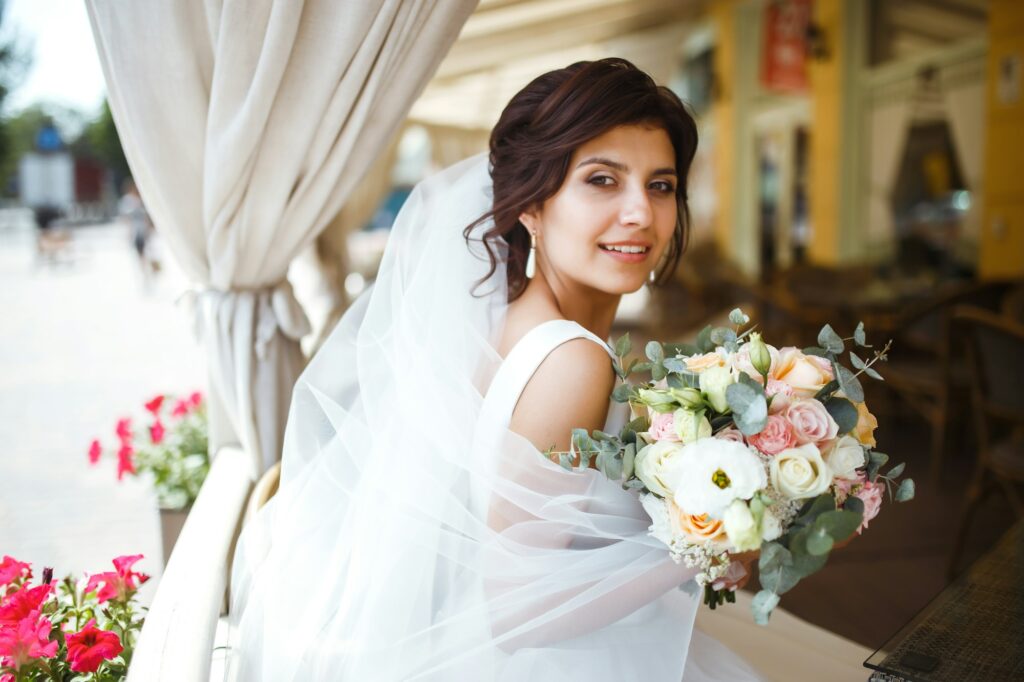 Beautiful bride with wedding flowers bouquet, attractive woman in wedding dress Happy newlywed woman
