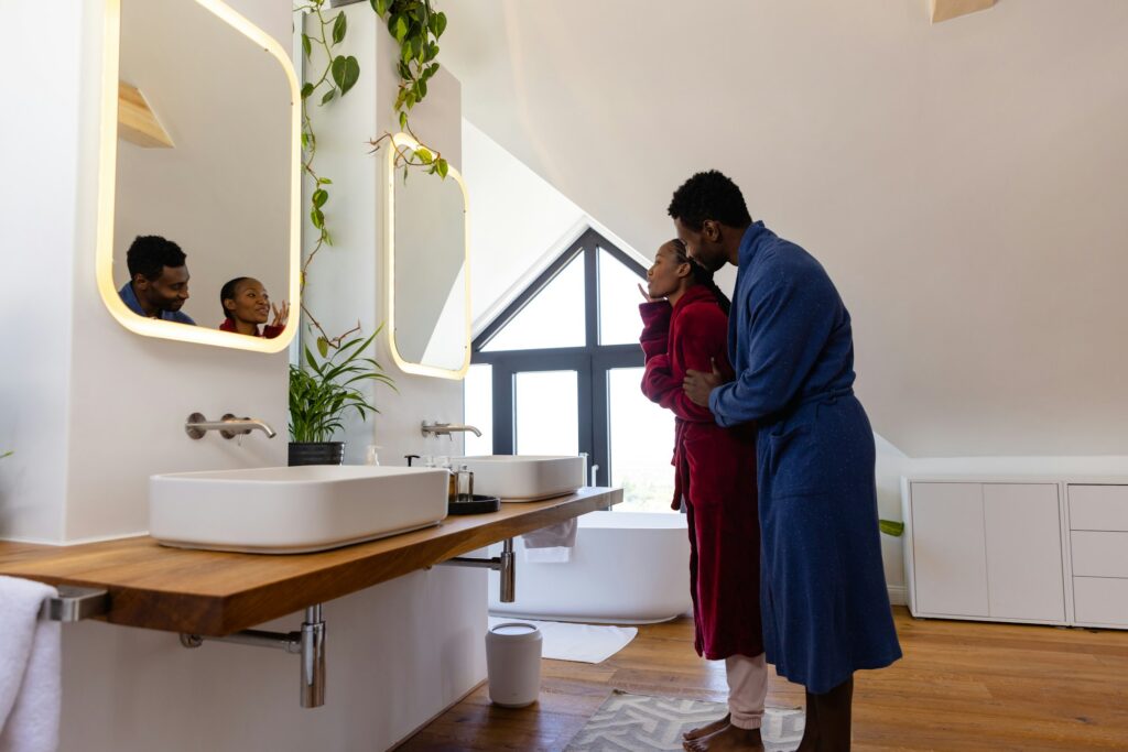 Happy african american couple in bathrobes embracing in bathroom At-Home Date Night Ideas for Couples