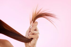 Woman, split end in hand and hair in studio for salon, hairdresser or repair shampoo or treatment.