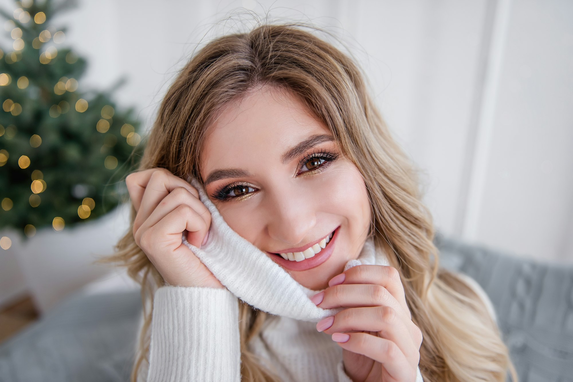 Close-up portrait of Fashion young woman with professional make-up, wraps face in a warm sweater