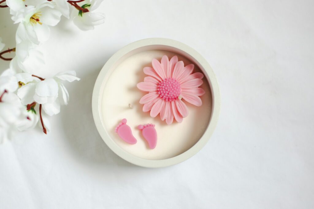 A pink flower in a white bowl next to white flowers